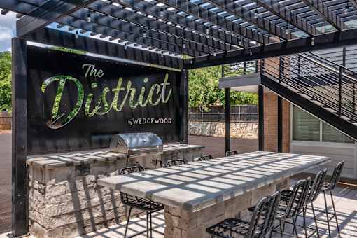 A sign that says "The District" is displayed in front of a patio area.