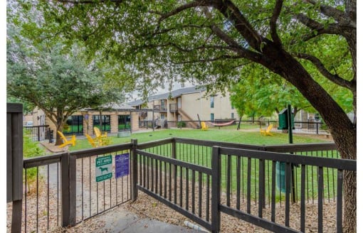 a fenced in area with a playground and trees at Cityscape, Dallas, TX