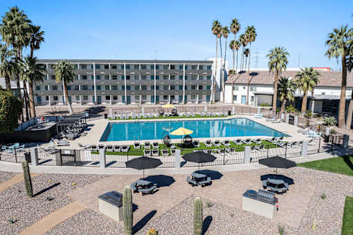 A pool surrounded by chairs and umbrellas with a building in the background at Presidio Palms Apartments, Tucson, AZ, 85701