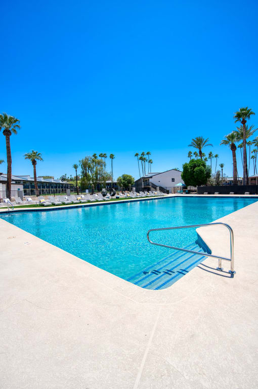 a swimming pool with palm trees and a building in the background at Presidio Palms Apartments, Arizona, 85701