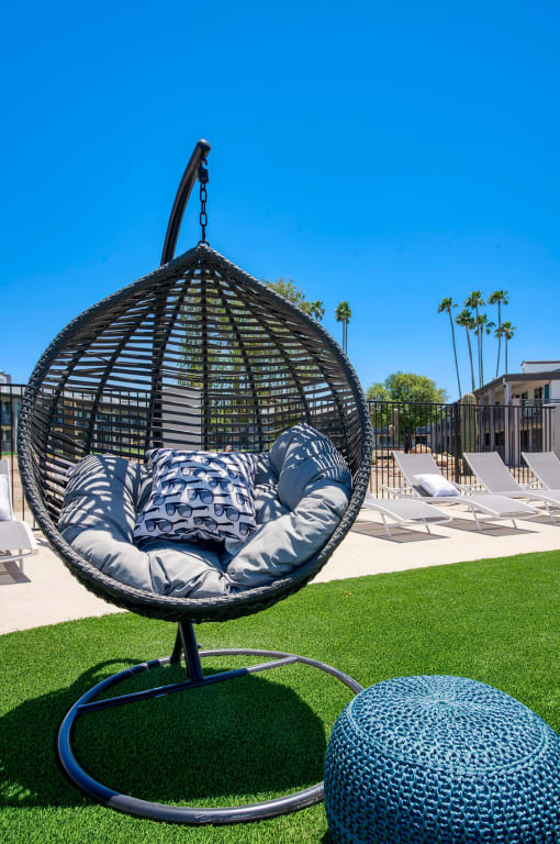 a swing chair with pillows on the grass at a pool at Presidio Palms Apartments, Tucson, Arizona