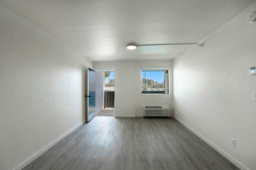 A spacious room with a door leading to a balconyat Presidio Palms Apartments, Tucson