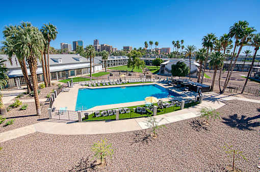 A pool surrounded by palm trees and a fence at Presidio Palms Apartments, Arizona, 85701