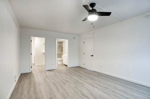 A room with a ceiling fan and light, and a wooden floorat Presidio Palms Apartments, Arizona