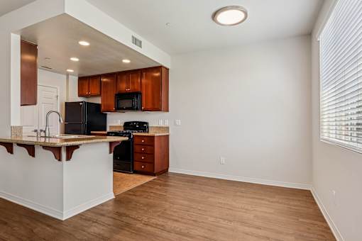 A kitchen with wooden cabinets and a black refrigerator.