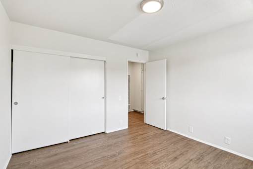 A bedroom with white walls and a wooden floor