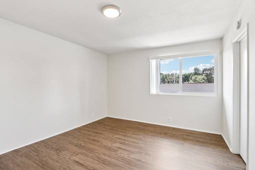 A living room with a window showing a view of trees outside.