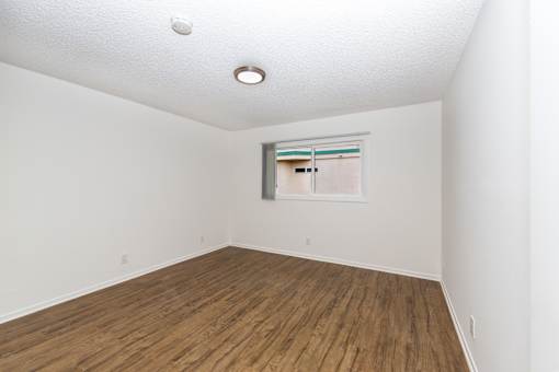 A room with wooden flooring and a window with blinds.