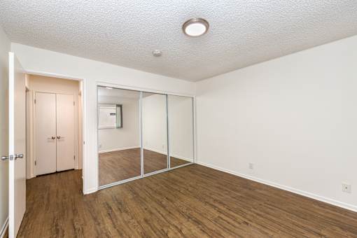 A bedroom room with a white ceiling and wooden flooring.