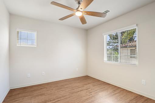 A room with a ceiling fan and a window with blinds.