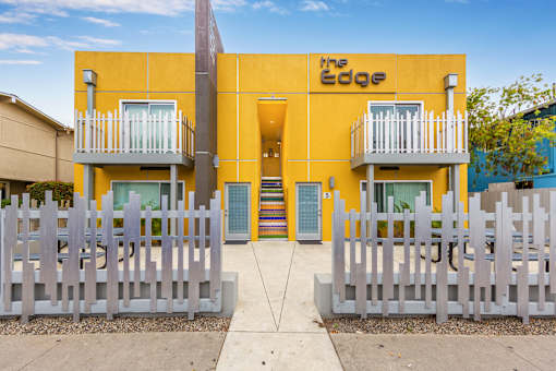 The Edge building has a yellow facade and white fences.