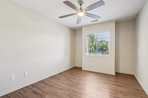A room with a ceiling fan and wooden flooring.