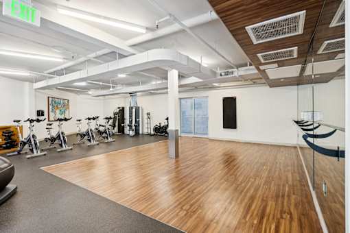 A gym with a variety of exercise equipment including treadmills, stationary bikes, and weights.
