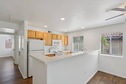 A kitchen with white appliances and wooden cabinets.