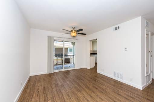 A room with a ceiling fan and wooden flooring.