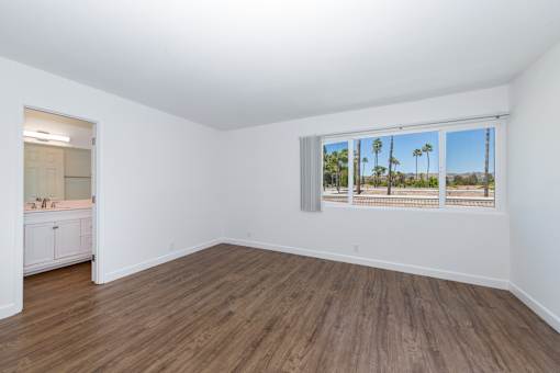 bedroom with a view of palm trees outside the window.