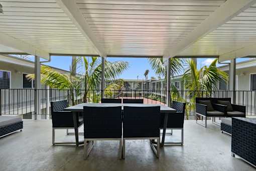 A patio with a table and chairs overlooking a balcony with plants.