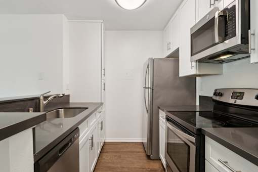 A kitchen with white cabinets and black countertops.