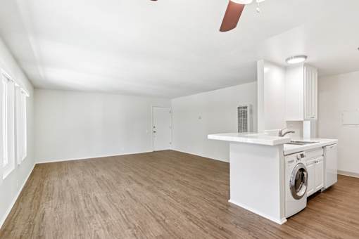 A white kitchen with a washing machine and a fan.