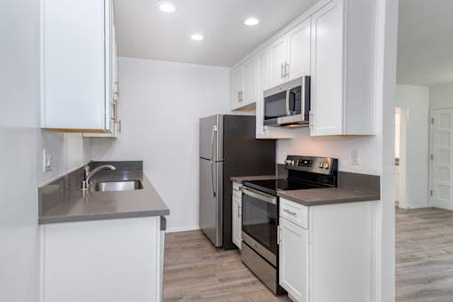 A modern kitchen with white cabinets and stainless steel appliances.