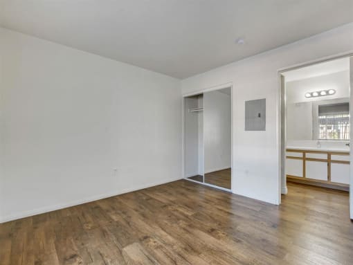 a bedroom with hardwood floors and white walls
