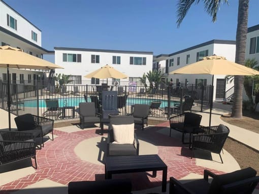 a large pool with chairs and umbrellas in a courtyard