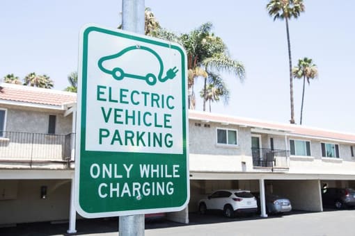 a green and white electric vehicle charging and parking sign in front of a building