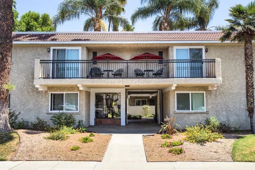 a house with a balcony and palm trees in the background
