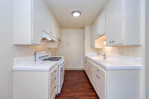 A white kitchen with a stove and sink.
