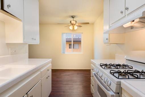 A kitchen with a white stove and cabinets.