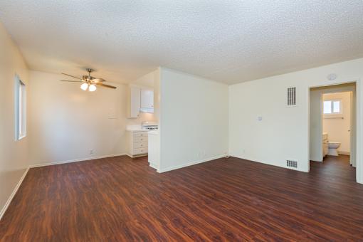 A living room with wood flooring and a ceiling fan.