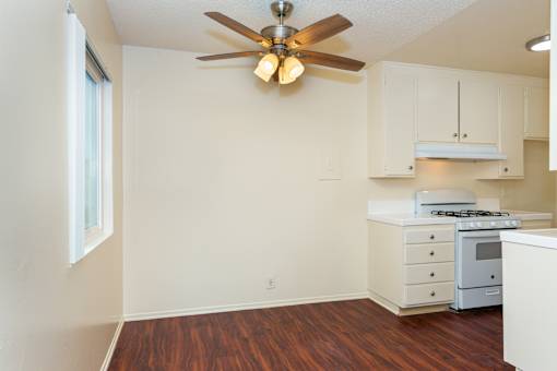 A kitchen with a wood floor and white walls.