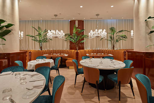 Elegant dining room with round tables and chandeliers at Bay One Apartments, Bayonne, New Jersey