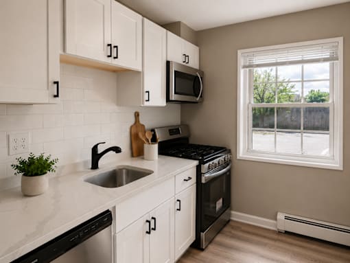 A kitchen with white cabinets and black countertops.