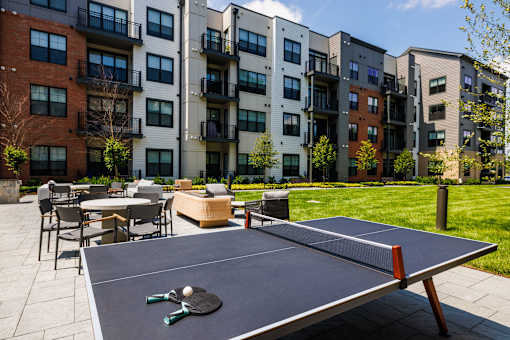 Outdoor courtyard with ping pong table and seating at Aster Grove Apartments, New Jersey
