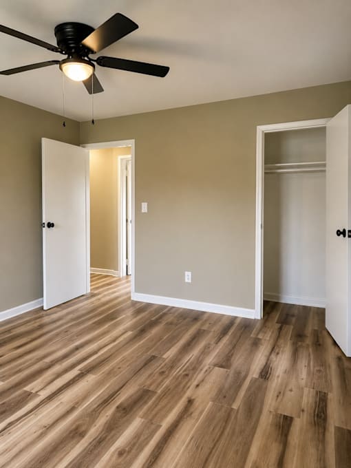 A room with a ceiling fan and wood flooring.