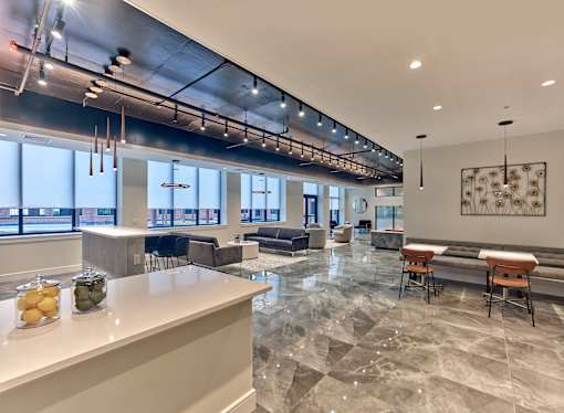a communal area with a bar and tables and chairs in a room with large windows