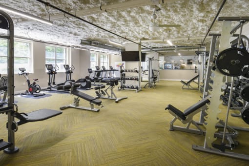 a gym with weights and cardio equipment in a building with exposed ceilings