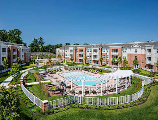Aerial view of pool courtyard with white pergola and landscaping at Highlands at Hilltop Apartments, Verona, NJ
