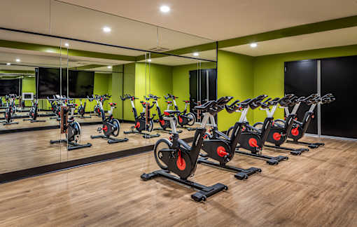 Indoor cycling studio with bikes and green accent wall at Inwood at Renaissance Square Apartments, New Jersey