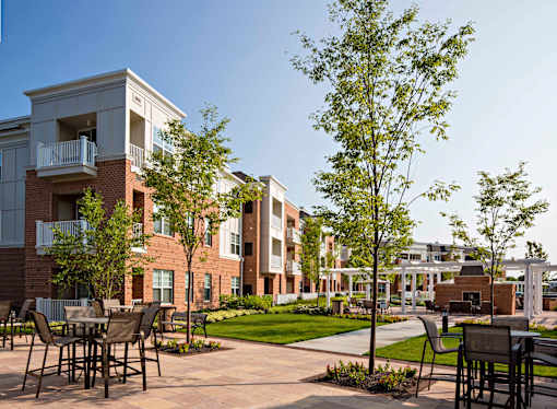 Courtyard seating area with bistro tables and mature trees at Highlands at Hilltop Apartments, New Jersey