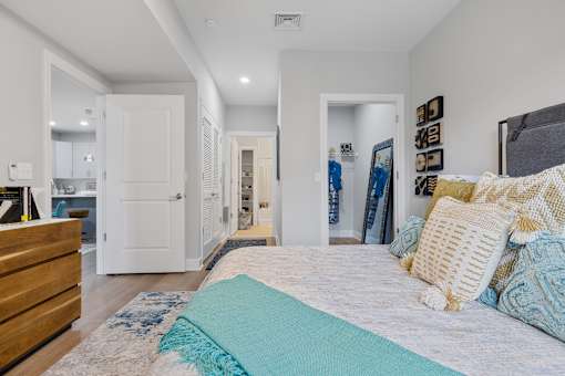 Bedroom with gray upholstered bed and hallway views at Highlands at Hilltop Apartments, Verona, 07044