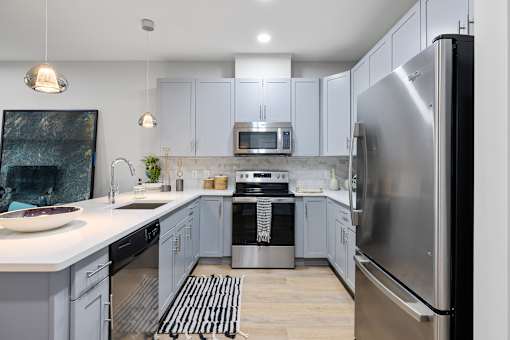 Modern kitchen with white countertops and stainless appliances at Highlands at Hilltop Apartments, New Jersey