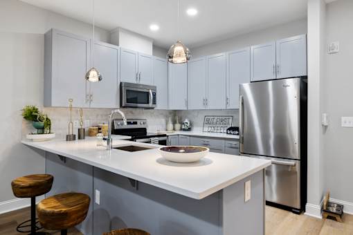 Modern kitchen island with pendant lighting and bar seating at Highlands at Hilltop Apartments, New Jersey, 07044