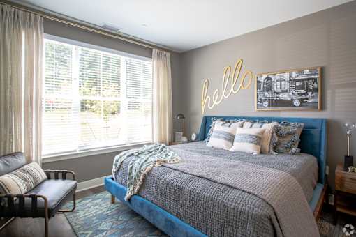Bedroom with blue upholstered bed and neon wall art at Inwood at Renaissance Square Apartments, Marlton, 08053