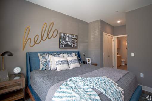 Bedroom with blue upholstered bed and ensuite bathroom at Inwood at Renaissance Square Apartments, New Jersey, 08053