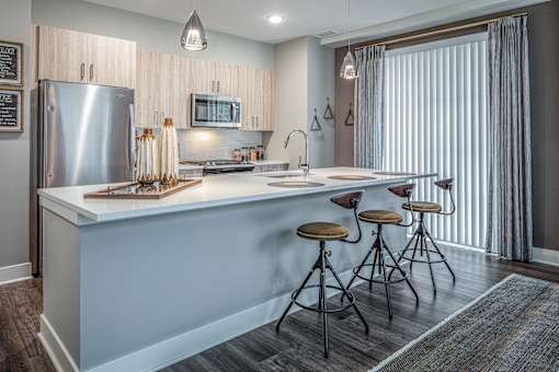Kitchen island with bar seating and vertical window blinds at Inwood at Renaissance Square Apartments, Marlton, 08053