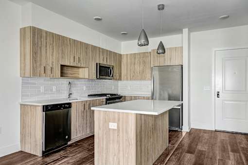 Kitchen with wood grain cabinetry and pendant lights at Inwood at Renaissance Square Apartments, Marlton, New Jersey