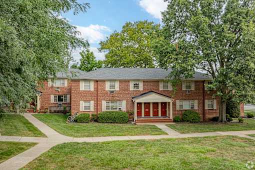 A red brick house with a green lawn in front.