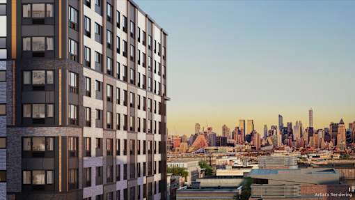 A tall building with many windows is in the foreground with a city skyline in the background.
